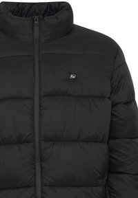 Svart polstret jakke med høy krage, frontglidelås og en liten logo på brystet. Laget av glatt, lett stoff med quiltede seksjoner.