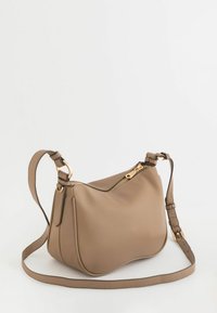 Beżowa torebka na ramię o fakturowanym wykończeniu z złotym zamkiem, pojedynczym regulowanym paskiem i zaokrąglonym kształtem. Posiada subtelną poświatę i przeszycia.