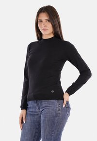 Maglione nero a maniche lunghe con colletto alto, caratterizzato da un design aderente e una texture sottile. Include un piccolo etichetta del marchio sull'orlo.