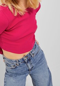 Fuchsia ribbad crop top i kombination med ljusblå högmidjade jeans i denim med avslappnad passform och blekt utseende.