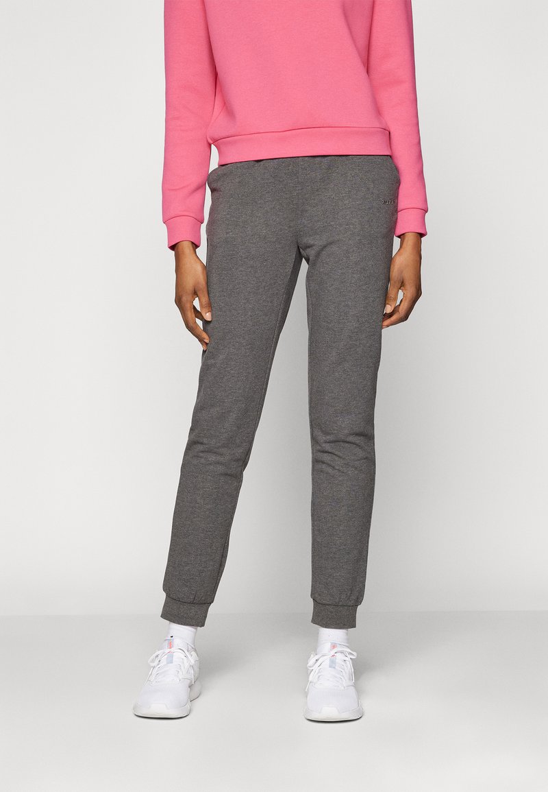 Grå joggebukser med en smal passform, elastiske mansjetter og en myk tekstur, kombinert med en lys rosa genser og hvite joggesko.