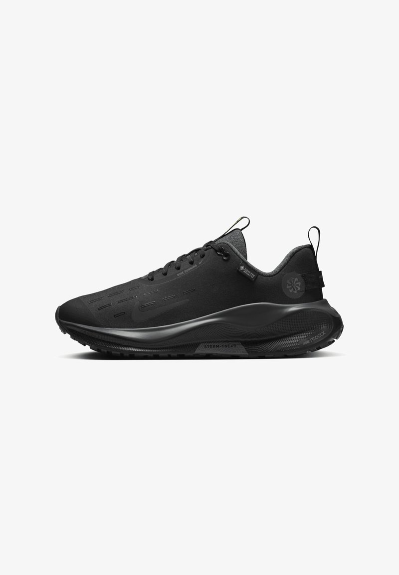 Chaussure de course noire basse avec semelle épaisse, laçage avant, languettes de traction au talon et à la languette, et étiquette Gore-Tex imperméable sur le côté.