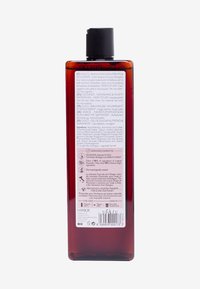 Kokosnöt som vårdar duschgel i en transparent amberflaska. Har ett svart lock, ingrediensdetaljer på baksidan på flera språk.