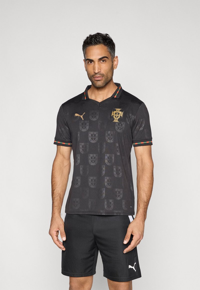 Camisola de futebol preta com um padrão subtil do brasão de armas de Portugal, logótipo dourado e gola às riscas vermelhas e verdes. Usada com calções pretos.