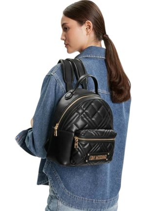 Zaino in ecopelle nero con motivo trapuntato, accessori tono oro, manico superiore e tasca frontale con zip. Sono visibili le cinghie regolabili.