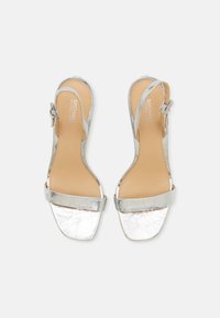 Sandale slingback argintii cu un finisaj texturat, crăpat, curea largă la gleznă și un design deschis la vârf, cu toc mic. Tălpică cu amortizare și branding.