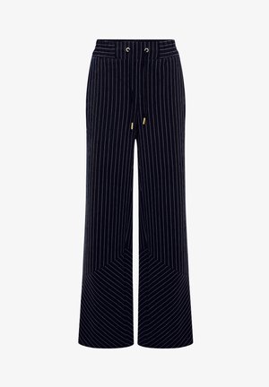 Pantaloni a gamba larga in corduroy blu scuro con strisce verticali bianche. Presentano una vita con coulisse e un dettaglio all'orlo angolato per un motivo geometrico.
