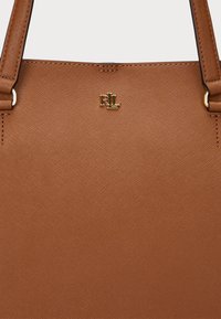 Brown synthetic leather tote bag with textured surface, gold-tone hardware, and embossed logo. Features two sturdy handles.