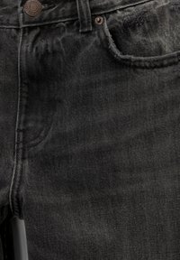 Jean en denim noir avec une texture légèrement délavée, présentant un design à cinq poches, et un bouton métallique à la taille pour la fermeture.