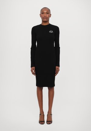Rochie neagră cu mâneci lungi, cu un design ajustat, până la genunchi, având un mic logo brodat pe piept. Textură netedă, material elastic.
