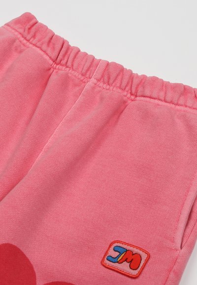 Rózsaszín pamut melegítőnadrág, elasztikus derékkal, kis hímzett logóval piros, kék és sárga színekben, puha tapintással.