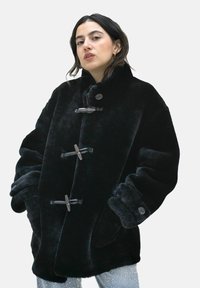 Schwarzer Kunstpelz-Mantel mit hohem Kragen, ausgestattet mit Knöpfen, weiten Ärmeln und einer weichen Textur. Einfarbig schwarz, keine Muster.