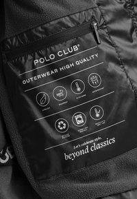 Czarna metka z białym napisem, zawierająca ikony przedstawiające cechy takie jak ultralekkość, wiatroszczelność, wodoodporność oraz wykonanie z poliestru pochodzącego z recyklingu.