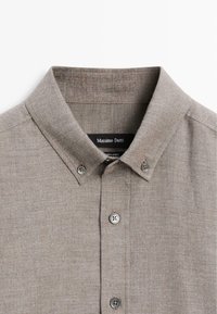 Linen shirt in light brown with a button-down collar, two button accents, and visible fabric texture. Label reads "Massimo Dutti."