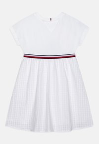 Weißes Kleid mit kurzen Ärmeln, bestehend aus einem unifarbenen Oberteil und einem strukturierten karierten Rock, akzentuiert durch einen rot-schwarz gestreiften Taillenbund.