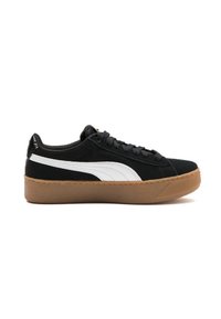 Zapatilla de ante negra con franja lateral blanca, diseño con cordones y suela de goma texturizada. Presenta un collar y lengüeta acolchados.