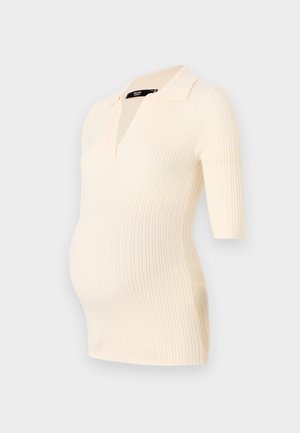 Cream ribbed maternity top with short sleeves and a polo collar, designed to fit comfortably over a growing belly.