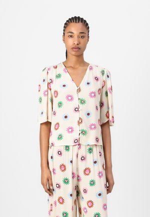 Short-sleeve, V-neck blouse in light beige fabric, adorned with colorful floral patterns in pink, blue, green, and brown. Features buttons down the front.