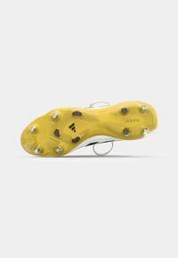 Yellow outsole of a soccer cleat featuring black accents, six metal studs, textured pattern, and a small logo on the side.