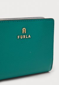 Turquoise leather wallet with textured finish, featuring a gold "FURLA" logo, neat stitching, and a compact rectangular shape.
