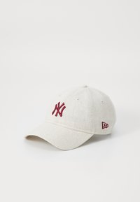 Casquette de baseball gris clair avec logo rouge brodé, visière courbée et détails en œillets ; présente une texture dans le tissu.