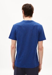 Blauwe, kortärmige T-shirt van textuurstof. Heeft een ronde halslijn en een ontspannen pasvorm, met een subtiel gemêleerd patroon.