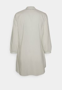 Camisa de manga longa verde-claro com riscas verticais, colarinho mandarim e um corte solto e alongado. Têxtil com textura suave.