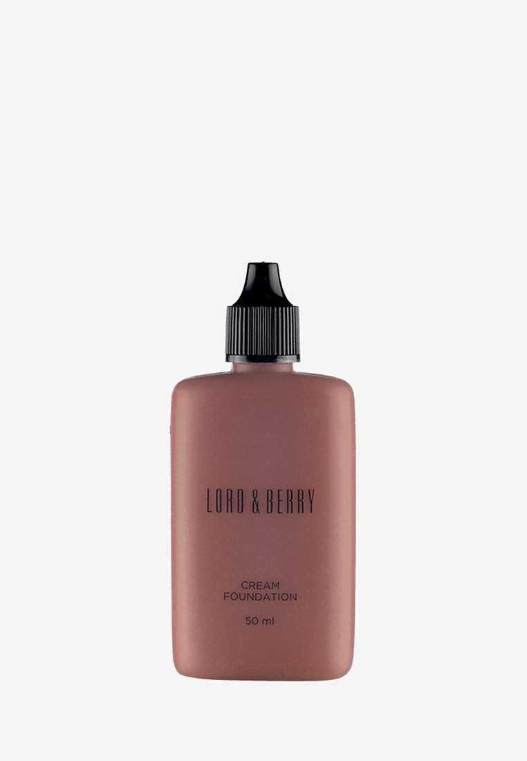 Flüssigfoundation-Flasche aus weichem rosa Kunststoff, mit schwarzem Schraubverschluss und engem Ausguss. Der Text zeigt den Markennamen und Produktdetails.