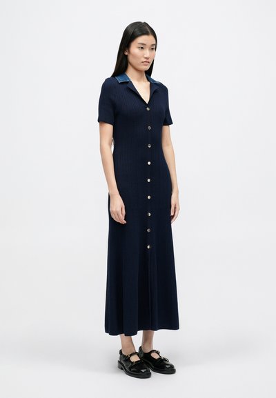 Tumes ribatakist dress lühikeste varrukatega, nööpide ees ja denimpihaga. Omab põrandani ulatuvat disaini ja kitsast siluetti.