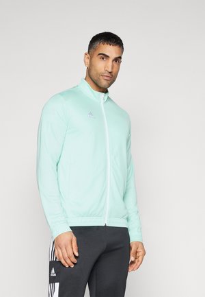 Light mint zip-up athletic jacket made of smooth fabric, featuring a high collar and subtle logo detail. Paired with dark jogger pants.