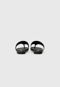 Sorte sandaler med minimalistisk design, med en glatt gumm tekstur, åpen tå og flat såle. Ingen synlig maskinvare eller aksenter.
