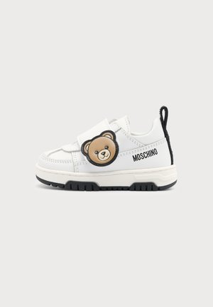 Biały dziecięcy sneaker z czarną podeszwą, twarzą misia na bocznym pasku i logo "Moschino" na zewnętrznej stronie.