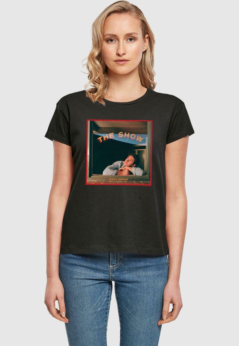 Tricou negru din bumbac cu un print grafic pătrat care ilustrează o persoană într-o fereastră, cu textul „THE SHOW” deasupra și „NIALL HORAN” dedesubt.