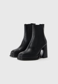 Botas de cuero negras hasta el tobillo con un alto tacón cuadrado, paneles elásticos en los laterales, punta redondeada y una textura suave, que ofrecen un diseño elegante.