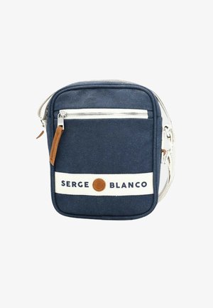 Sac en toile marine à bandoulière avec une sangle blanche, doté d'une poche zippée à l'avant, de détails en cuir brun et d'un texte "SERGE BLANCO".