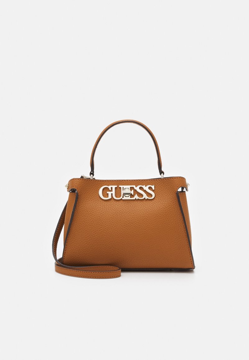 Sac à main en cuir marron avec une conception structurée, doté d'une poignée supérieure et d'une bandoulière réglable, logo "GUESS" embossé en métal argenté.