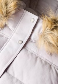Lichtroze winterjas met bontafwerking aan de capuchon en drukknoopsluiting aan de voorkant.