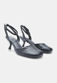 Black leather slingback shoes with a rounded toe, slender heel, and adjustable ankle strap. Smooth texture and minimalist design.