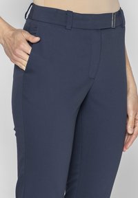Granatowe spodnie o dopasowanym kroju z elastycznego materiału, z bocznymi kieszeniami, prostą nogawką i metalowym zapięciem na pasku.