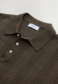 Bruine gebreide polo met een kraag, voorzien van drie knopen en verticale ribbelpatronen. Het label bij de halslijn draagt de tekst "next".