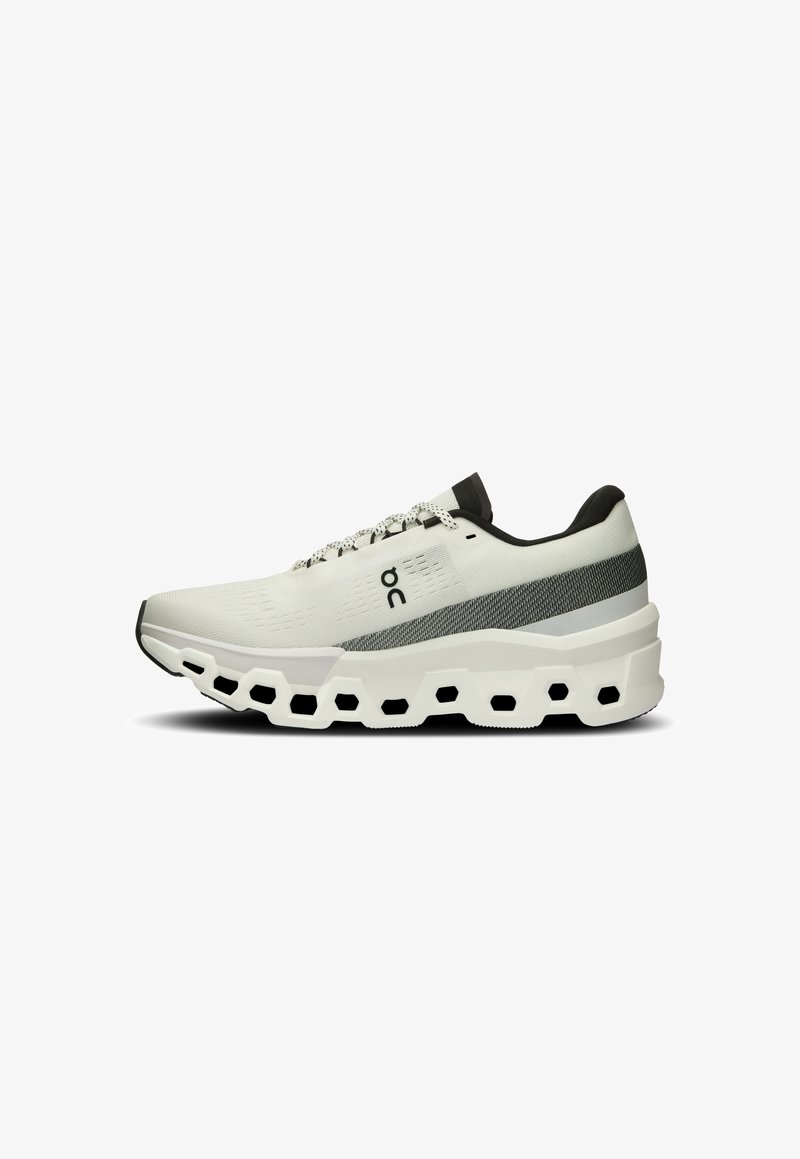 Chaussure de sport blanche avec une tige en tricot texturé, une bande grise, et une semelle épaisse et rembourrée avec des découpes hexagonales pour plus de flexibilité.