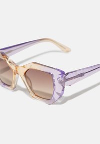 Hexagonale solbriller i lys lilla og amber rammer, med gradient brune linser og aksenter med gull "GUESS" merke.