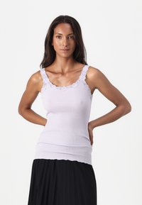 Vaaleanvioletti ribattu tank top, jossa on pitsireunus kaula-aukon ja olkaimien ympärillä. Sovitettu malli, joka on kerroksittain mustan pliseeratun hameen alla.