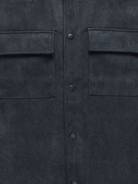 Veste en daim foncé avec deux poches horizontales sur la poitrine, boutons-pression noirs, et une texture douce. Présente une finition lisse et des lignes épurées.