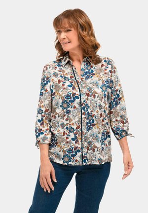 Blumenbluse mit Kragen; verfügt über blau-, rot- und braunfarbene Muster auf weißem Hintergrund; Dreiviertelärmel mit Bindebändern.