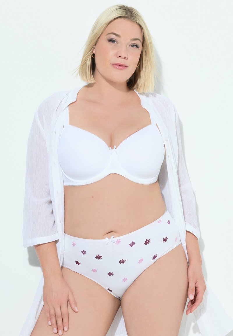 Bílý podprsenkový korzet s měkkými košíčky, spárovaný s bílými kalhotkami s vysokým pasem, které mají květinový vzor v růžové a hnědé barvě. Lehký průsvitný přehoz.