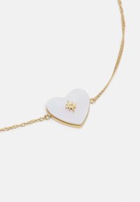 Collana d'oro con pendente a forma di cuore in pietra bianca caratterizzato da un design a stella. Il pendente ha una superficie texturizzata e una delicata catena.