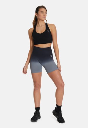 Zwarte sportbh gecombineerd met grijs ombre high-waisted shorts. De stof is soepel met een aansluitend ontwerp, voorzien van een logo op het linkerbeen.