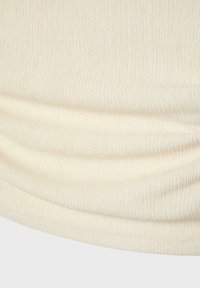 Tissu couleur crème avec de fines lignes texturées verticales et de doux plis horizontaux sur une surface lisse.