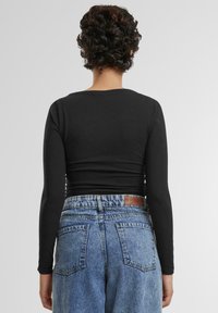 Svart langermet topp kombinert med høy midje lys blå denim jeans, som viser en avslappet passform og klassisk fem-lommersdesign.